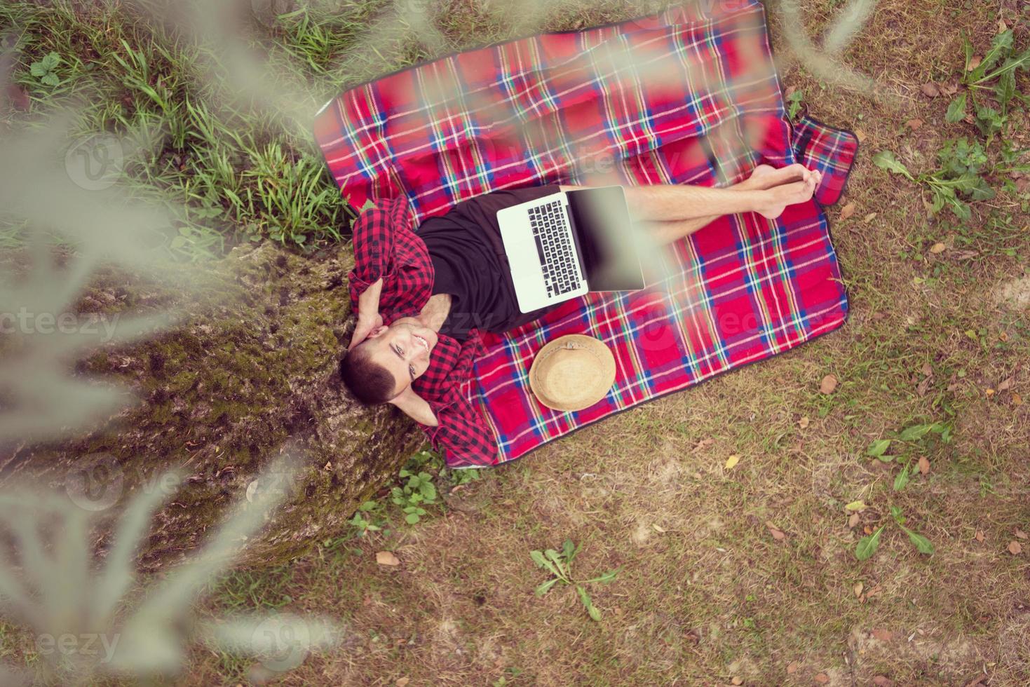 top view of man using a laptop computer under the tree photo