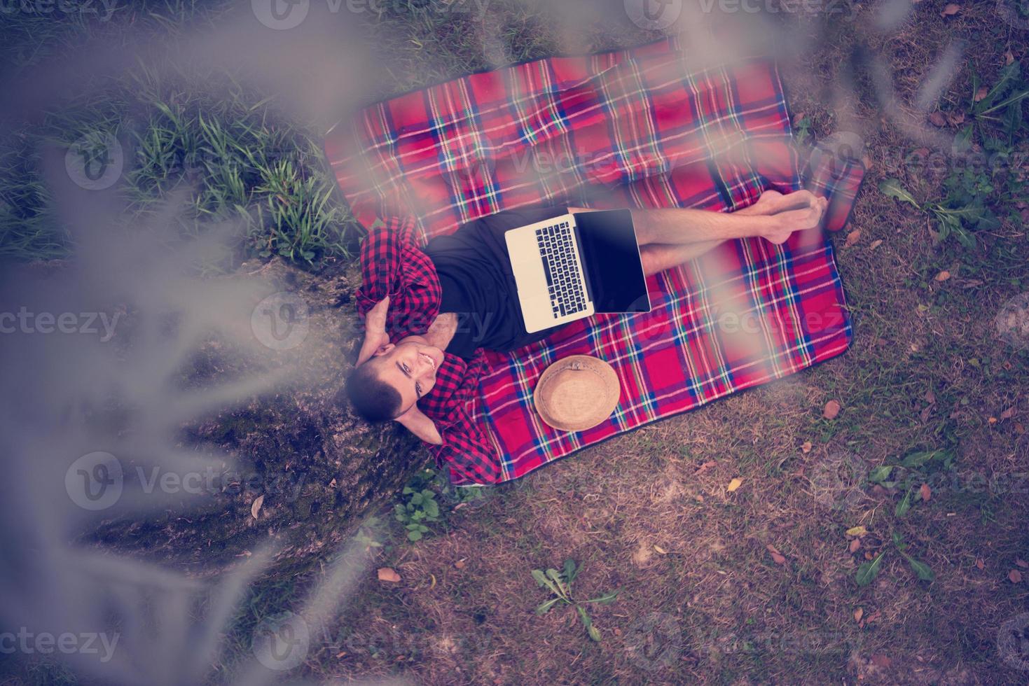 top view of man using a laptop computer under the tree photo