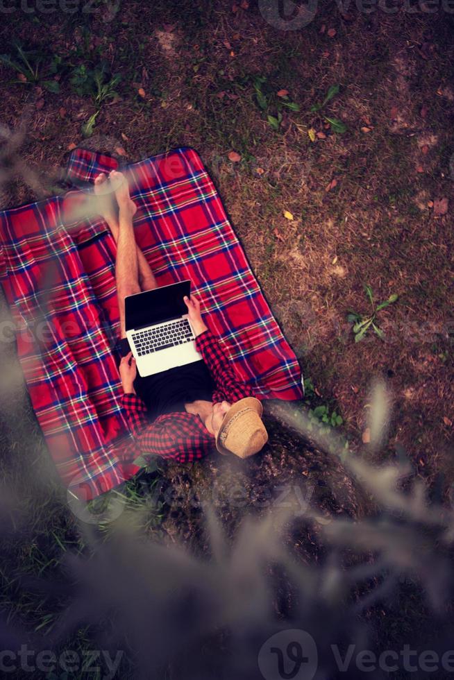 top view of man using a laptop computer under the tree photo
