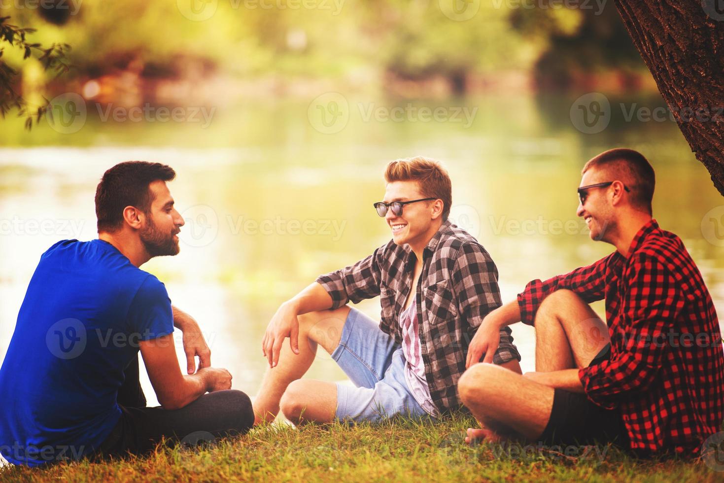 men sitting on the bank of the river photo