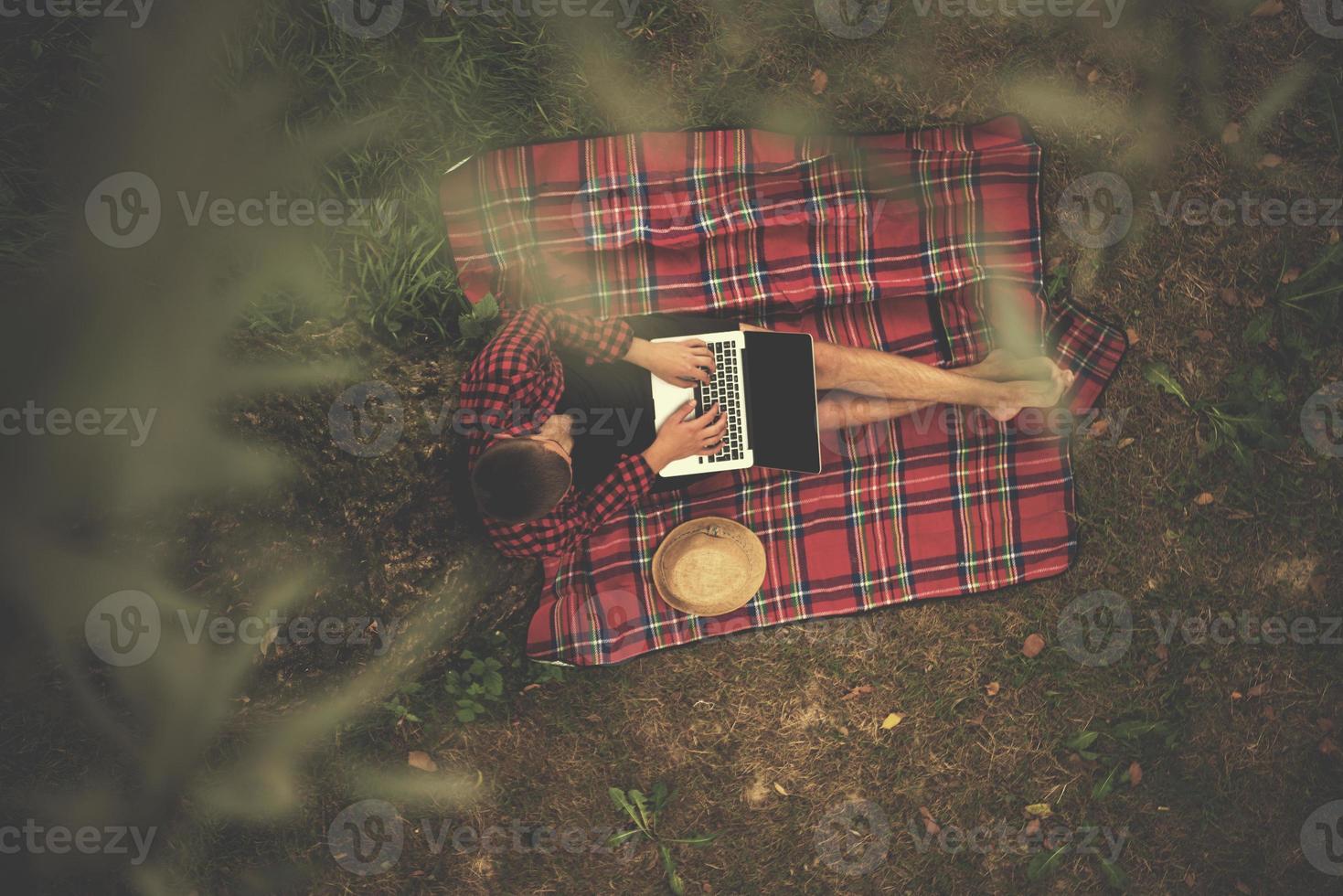 top view of man using a laptop computer under the tree photo