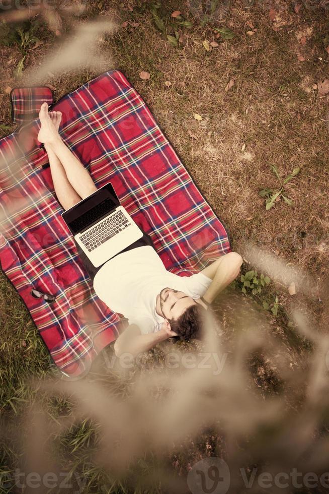 top view of man using a laptop computer under the tree photo