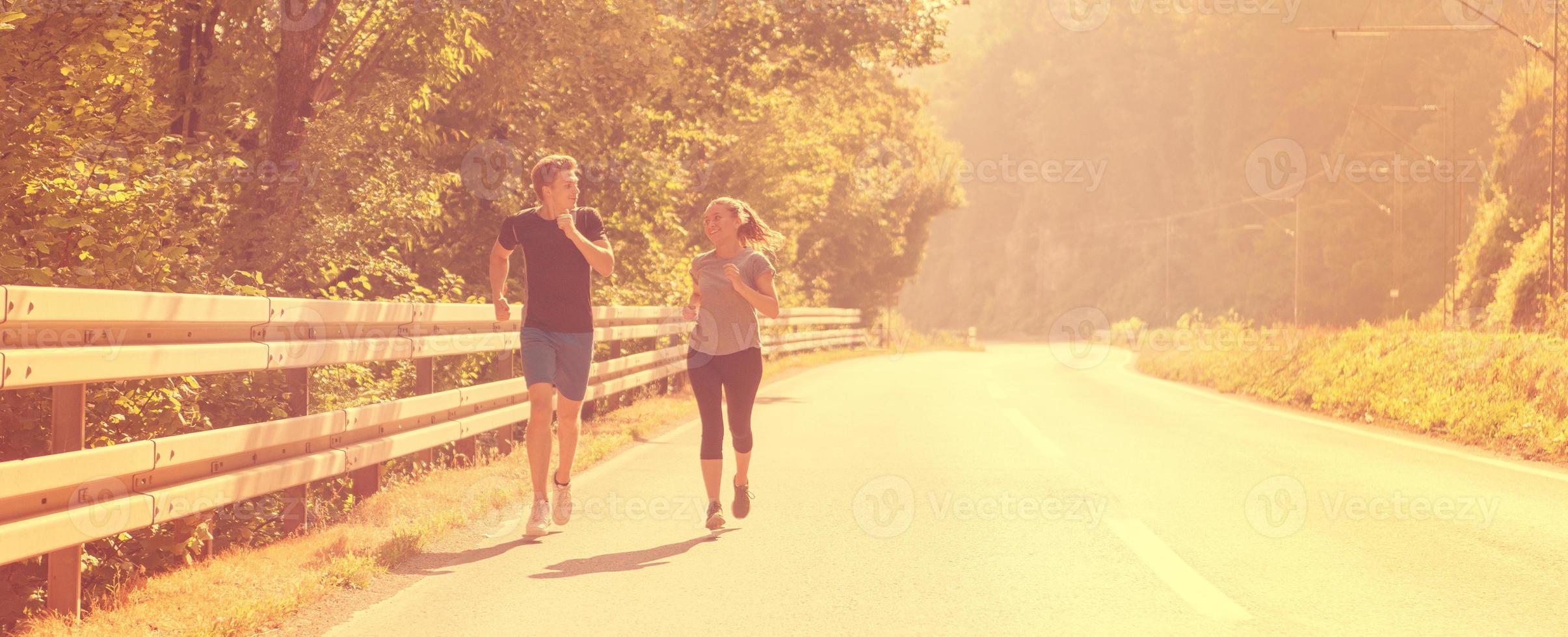 pareja joven trotando a lo largo de un camino rural foto