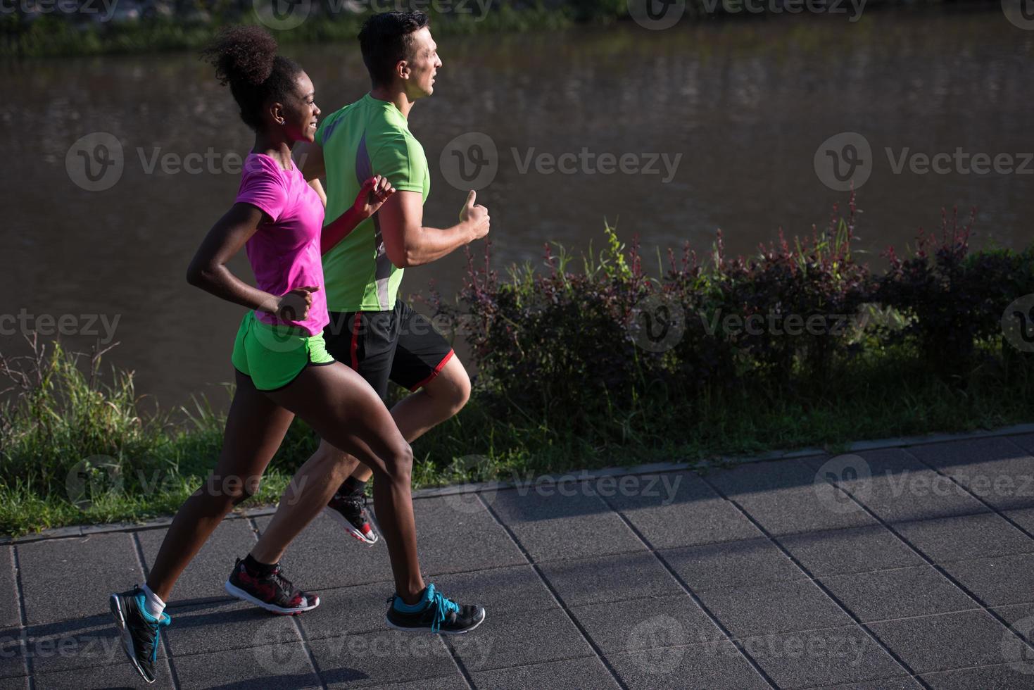 young smiling multiethnic couple jogging in the city photo