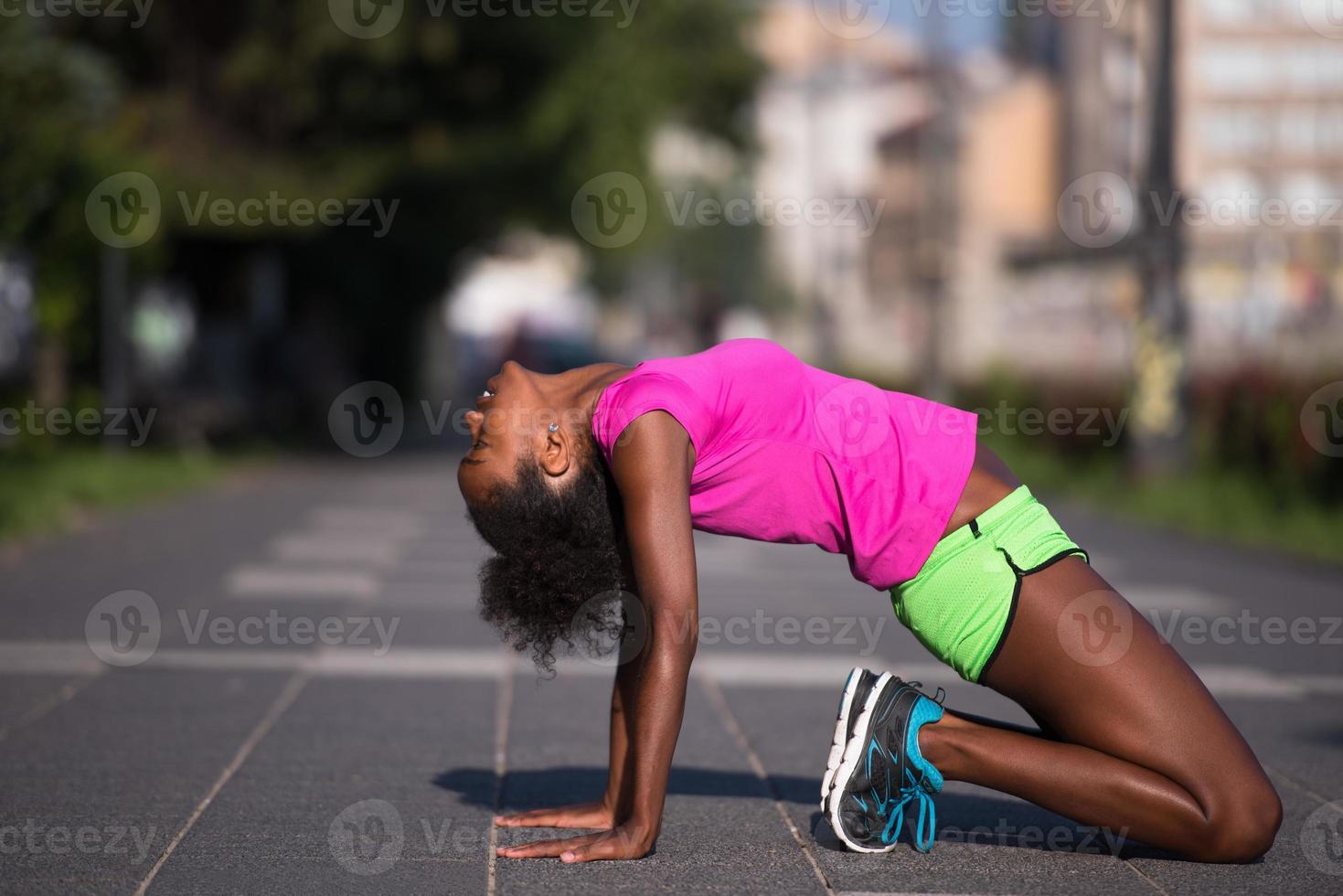 sporty young african american woman stretching outdoors photo