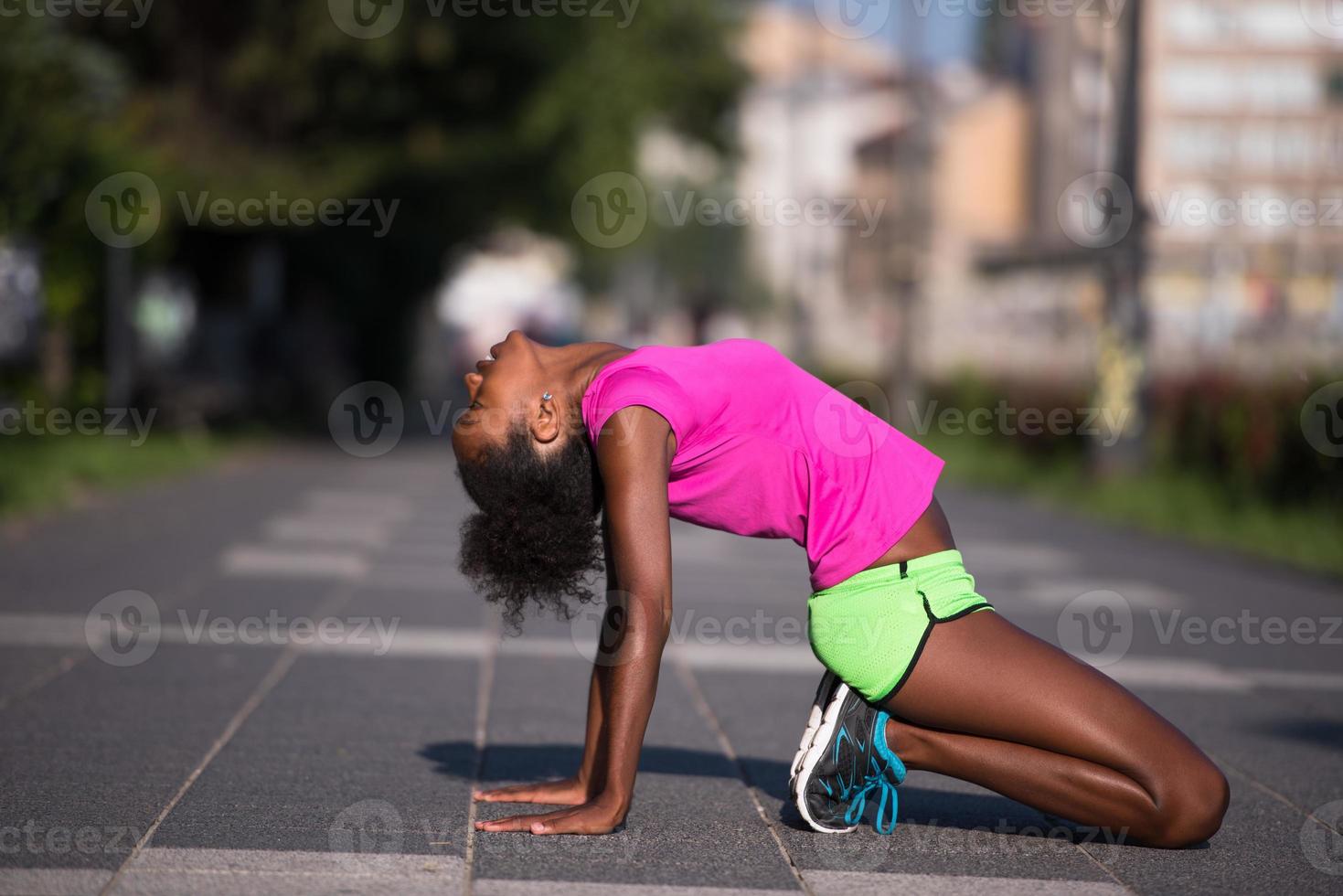 sporty young african american woman stretching outdoors photo