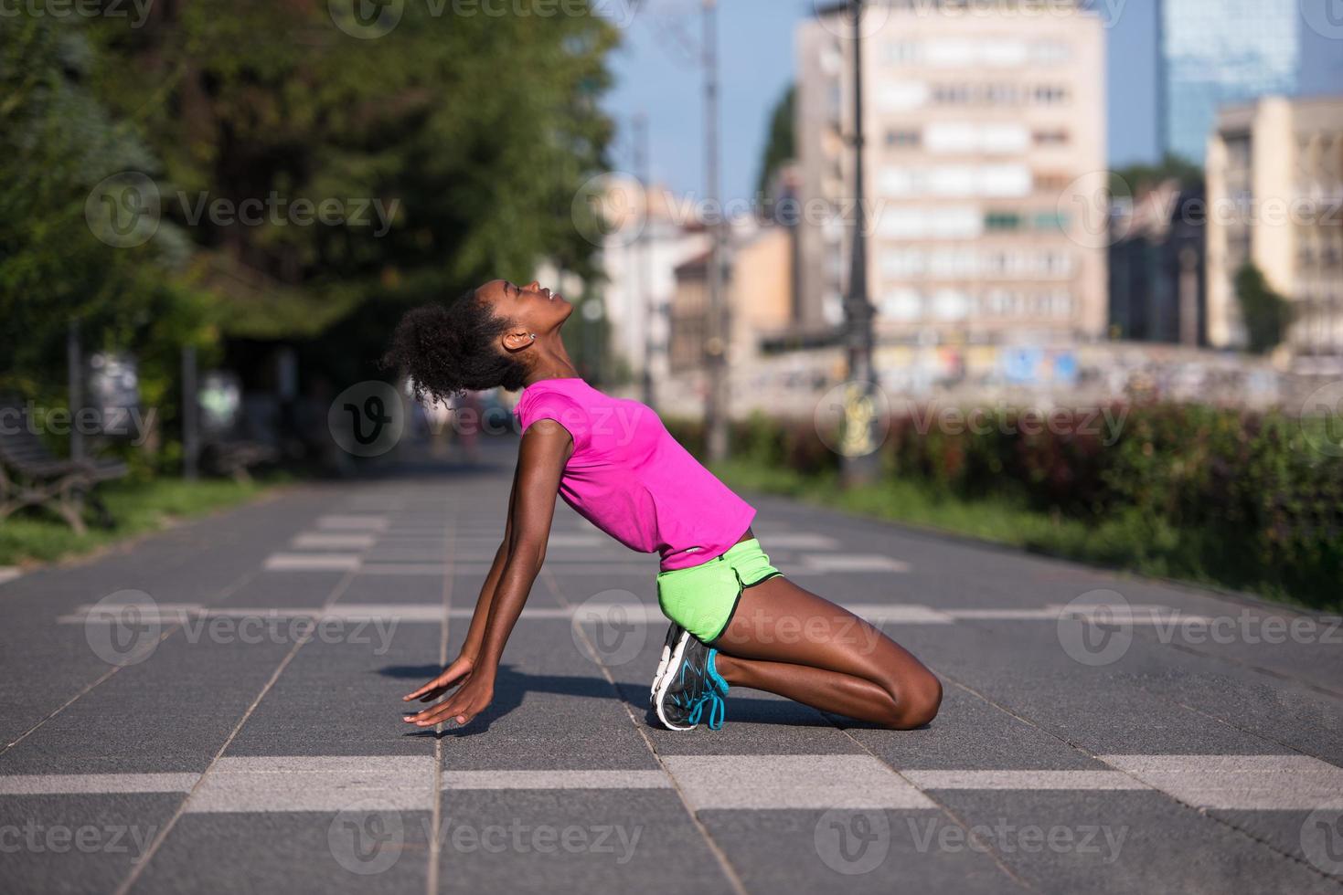 sporty young african american woman stretching outdoors photo