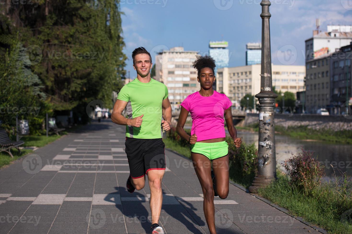 young smiling multiethnic couple jogging in the city photo