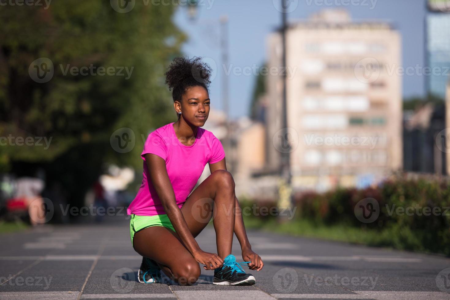 Mujer afroamericana runner apretando los cordones de los zapatos foto