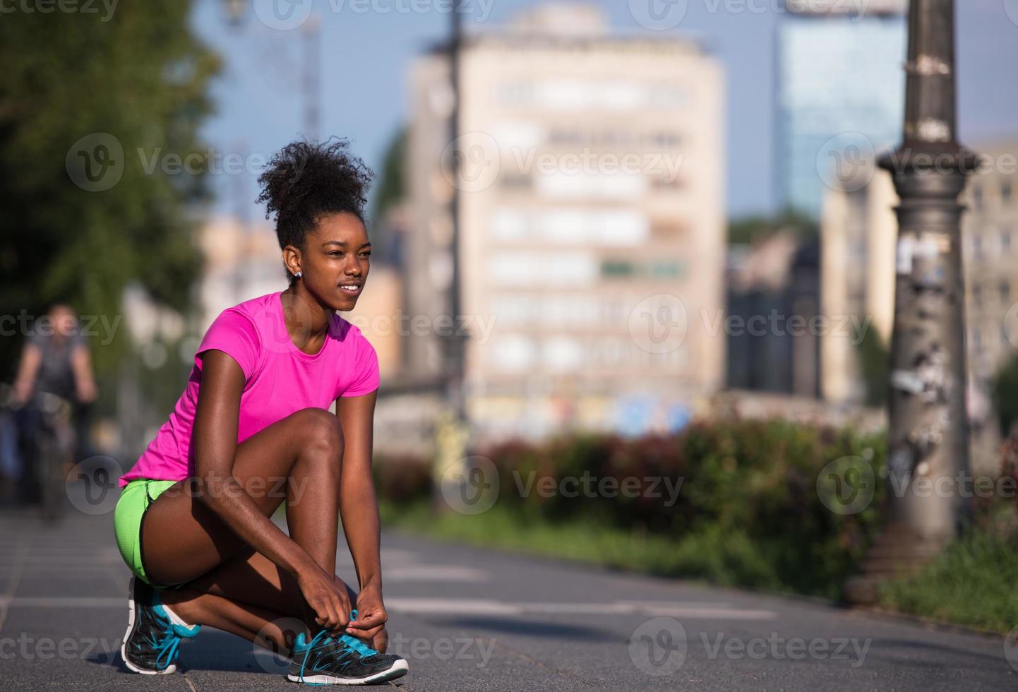 Mujer afroamericana runner apretando los cordones de los zapatos foto