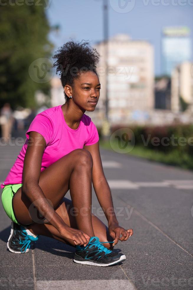 Mujer afroamericana runner apretando los cordones de los zapatos foto