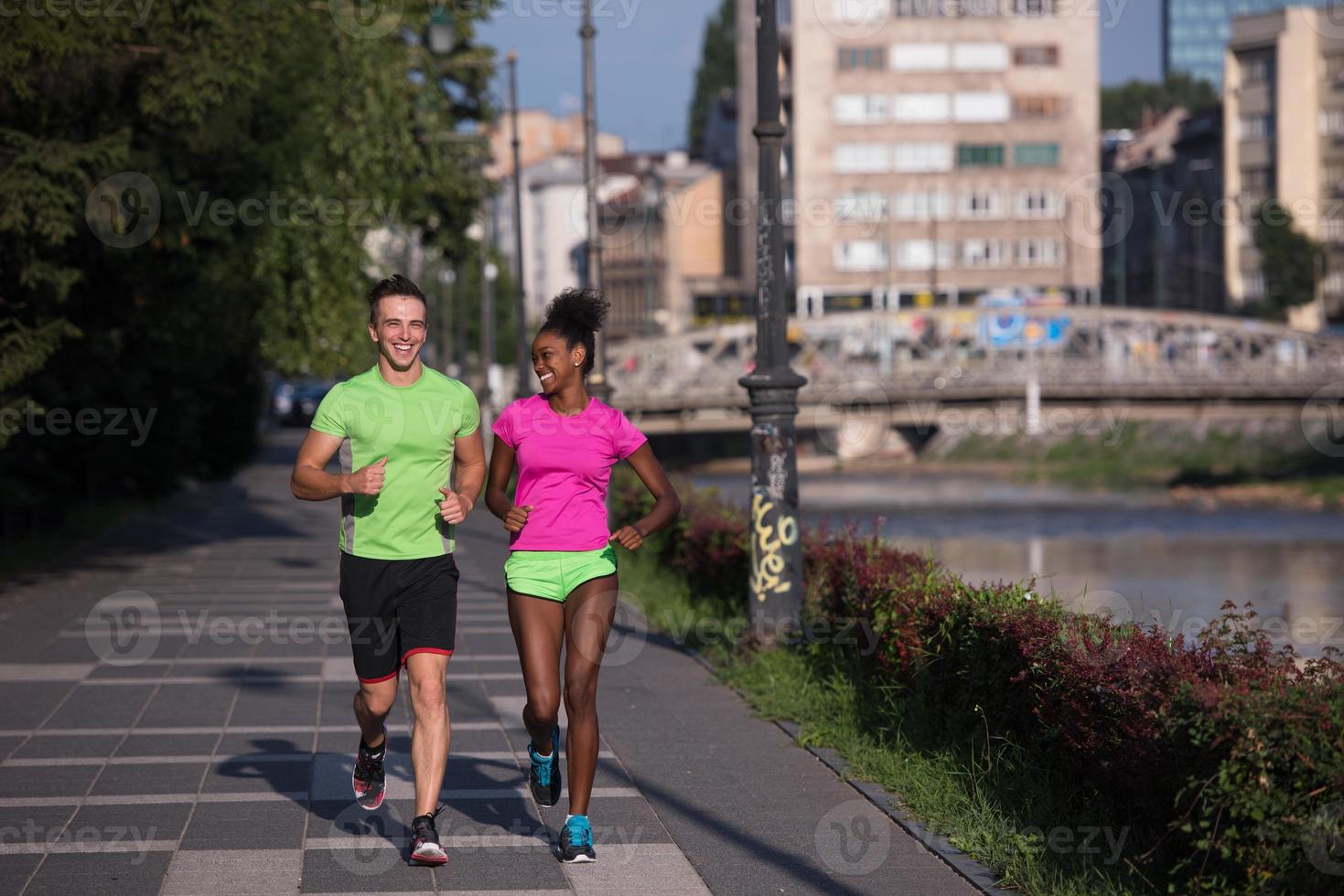 young smiling multiethnic couple jogging in the city photo