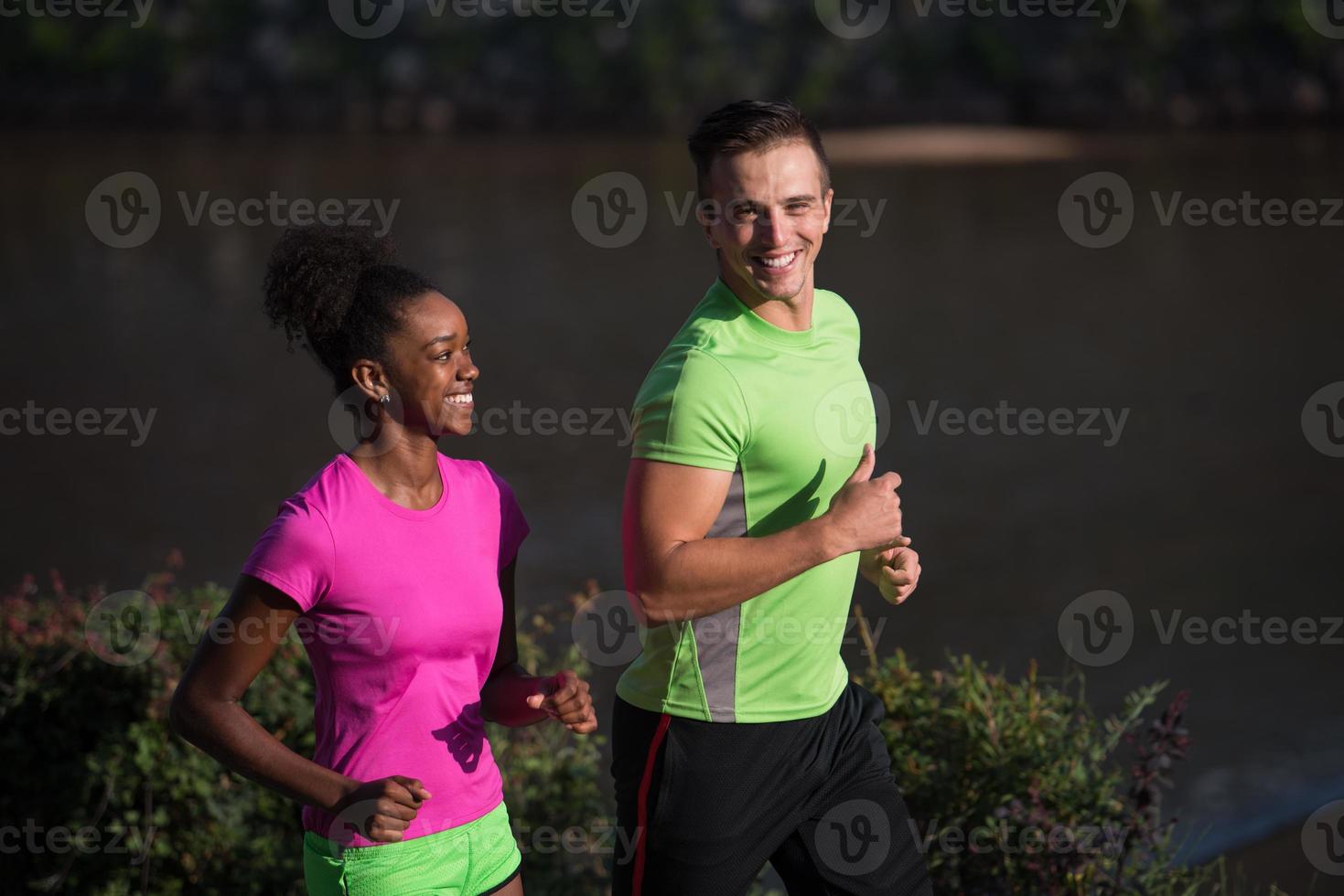 young smiling multiethnic couple jogging in the city photo