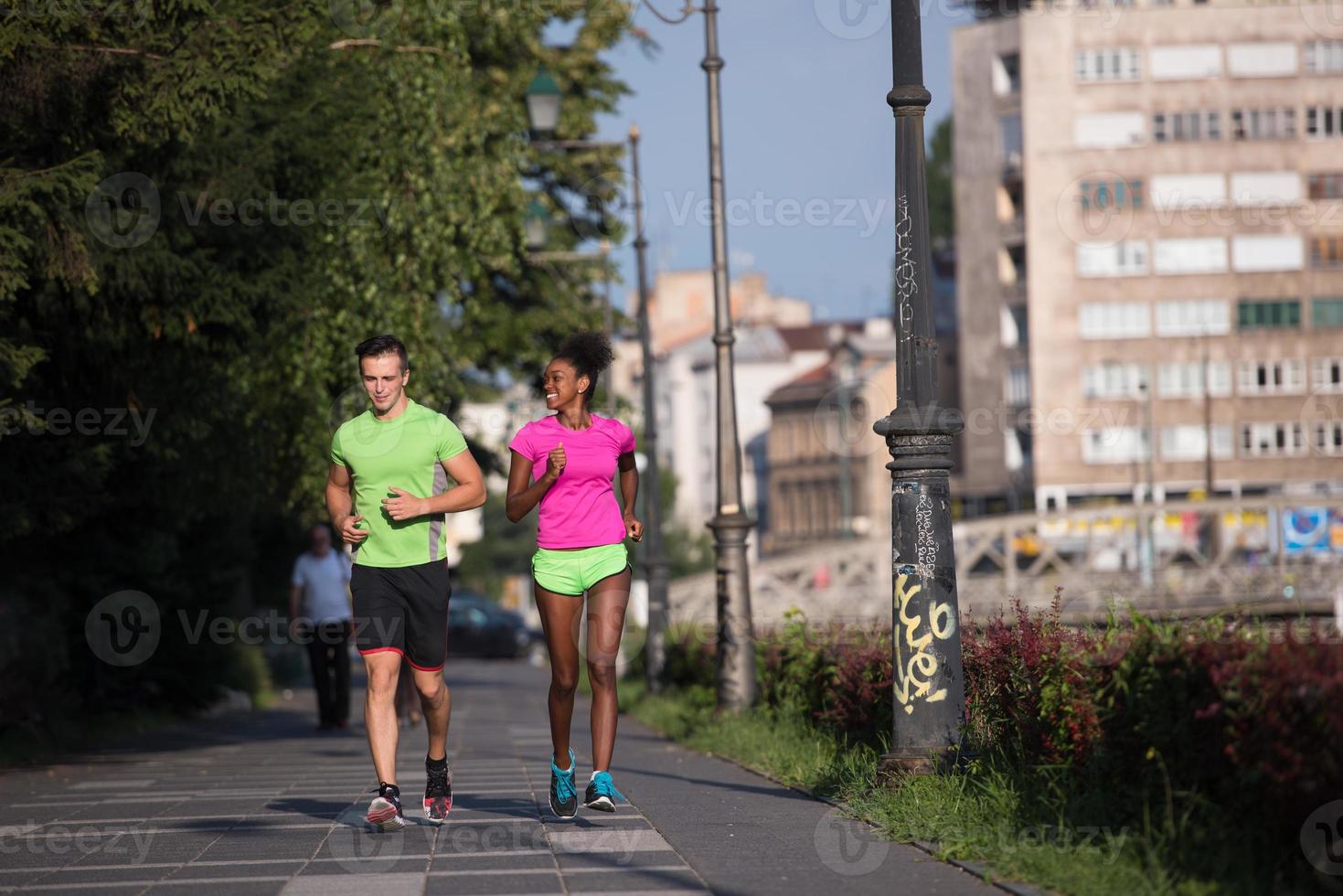 young smiling multiethnic couple jogging in the city photo