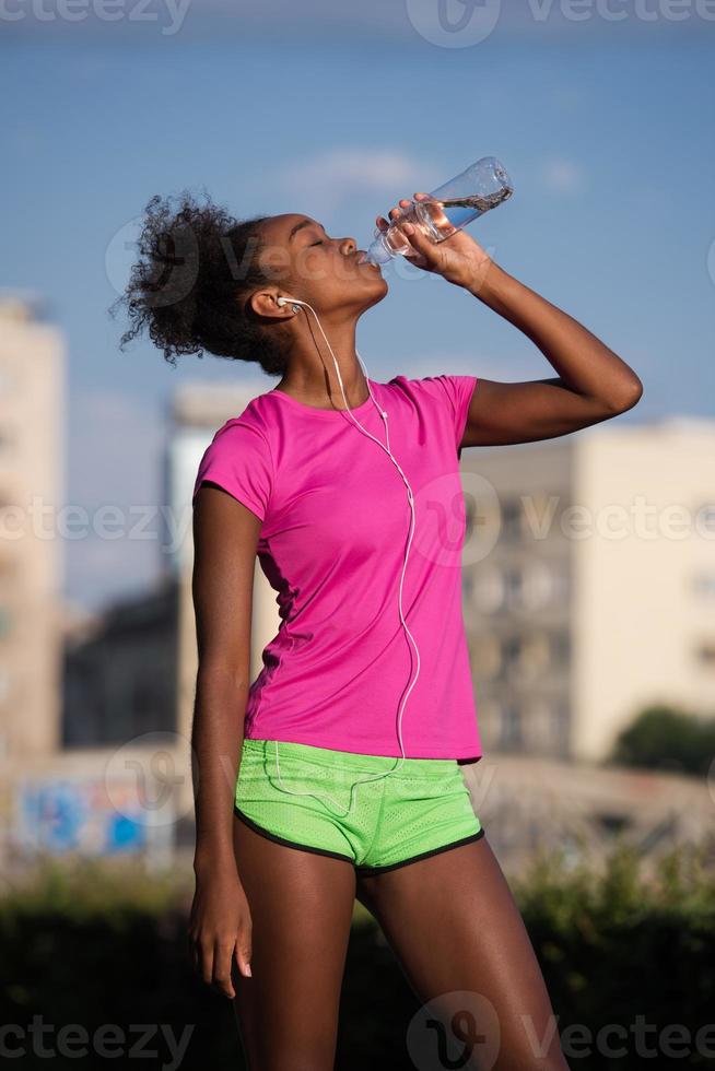 african american woman drinking water after jogging photo