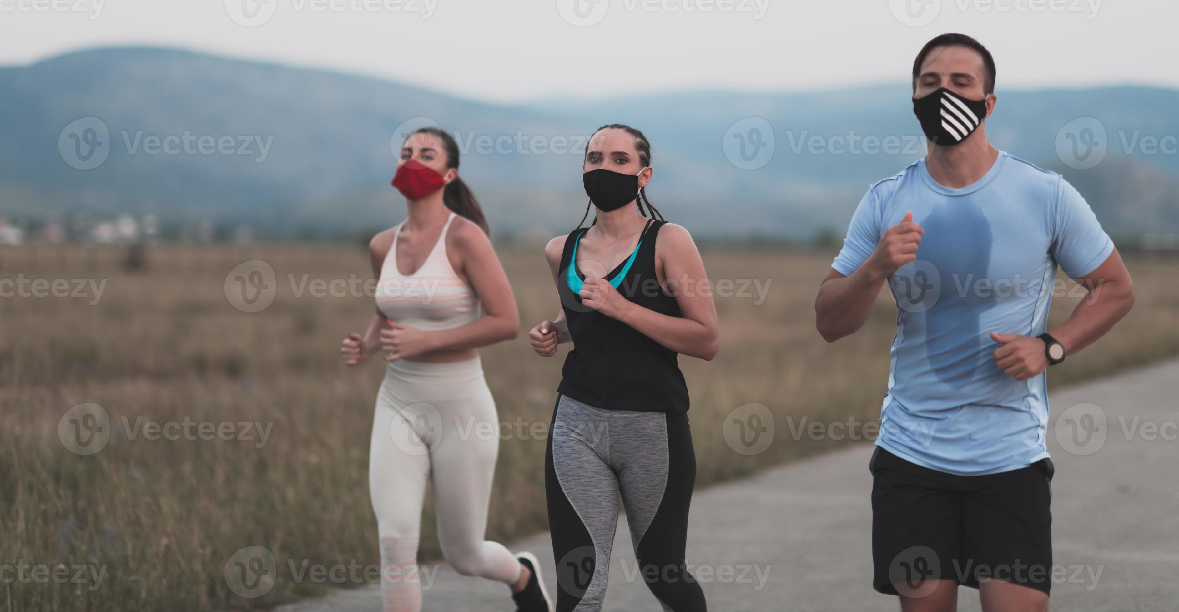 Three multiethnic women runners group wear face masks running