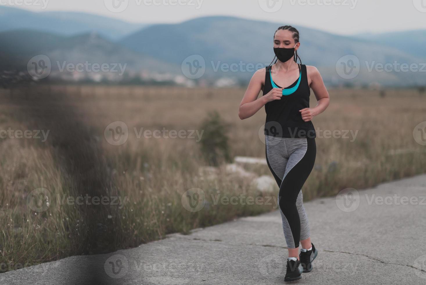 determinada mujer fitness con ropa corta y mascarilla protectora roja corriendo al aire libre en la ciudad durante el brote de coronavirus. covid 19 y actividad física de jogging, deporte y fitness. foto