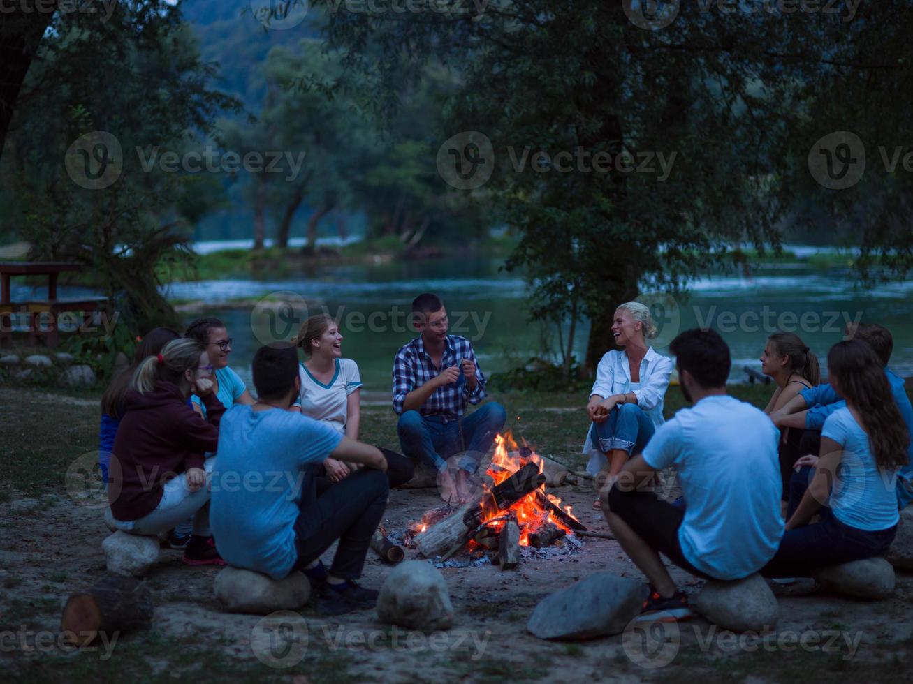 young friends relaxing around campfire photo