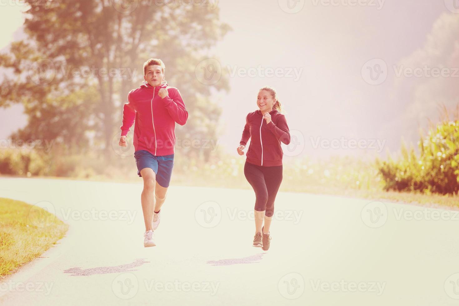 young couple jogging along a country road photo