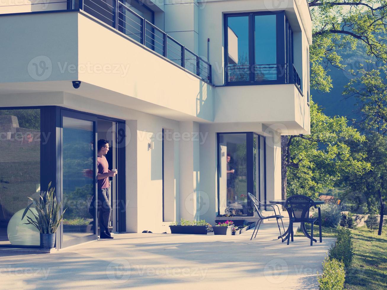 man drinking coffee in front of her luxury home villa photo