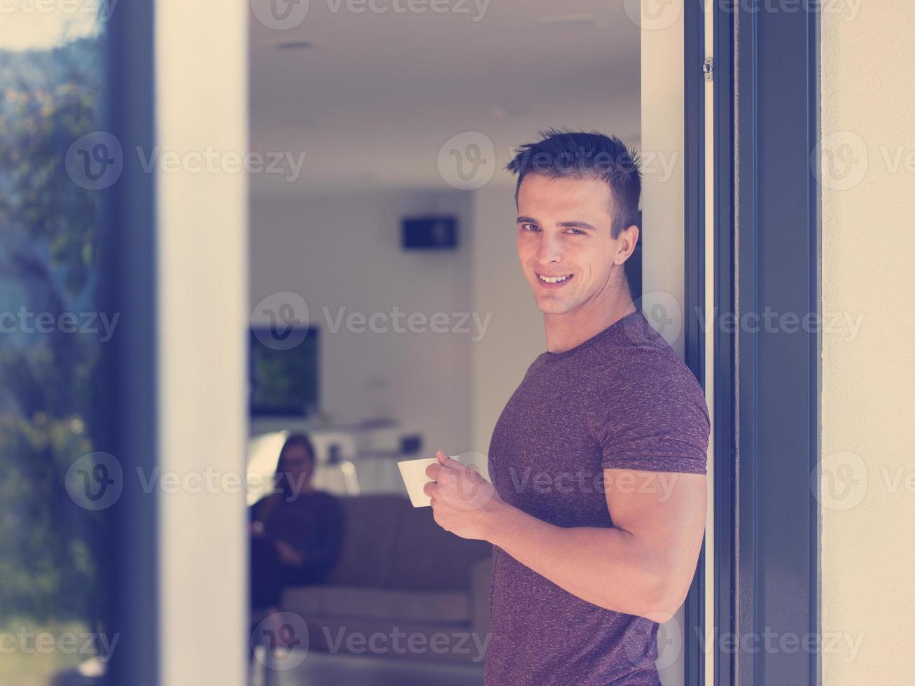 man drinking coffee in front of her luxury home villa photo