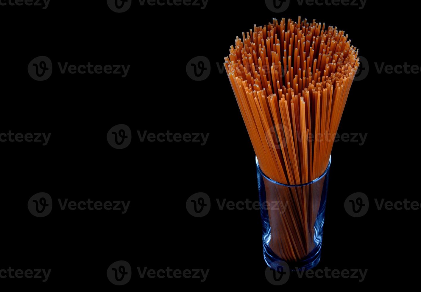 Long pasta isolated on black background. Red tomato pasta. Italian pasta in a glass glass. photo