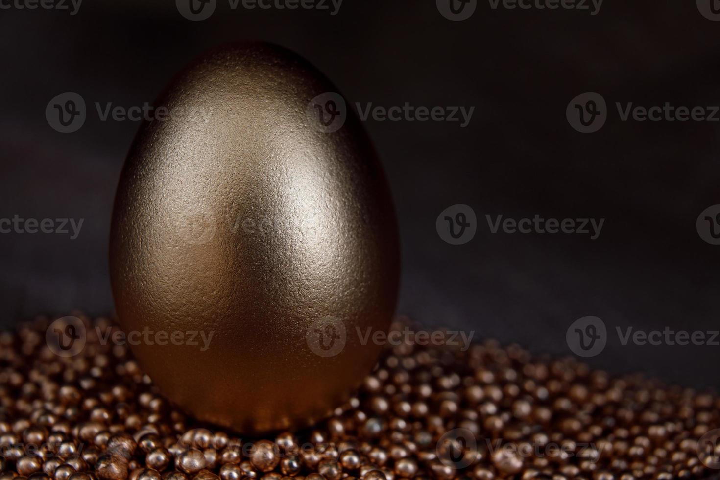 The golden egg stands on the gold sand. photo