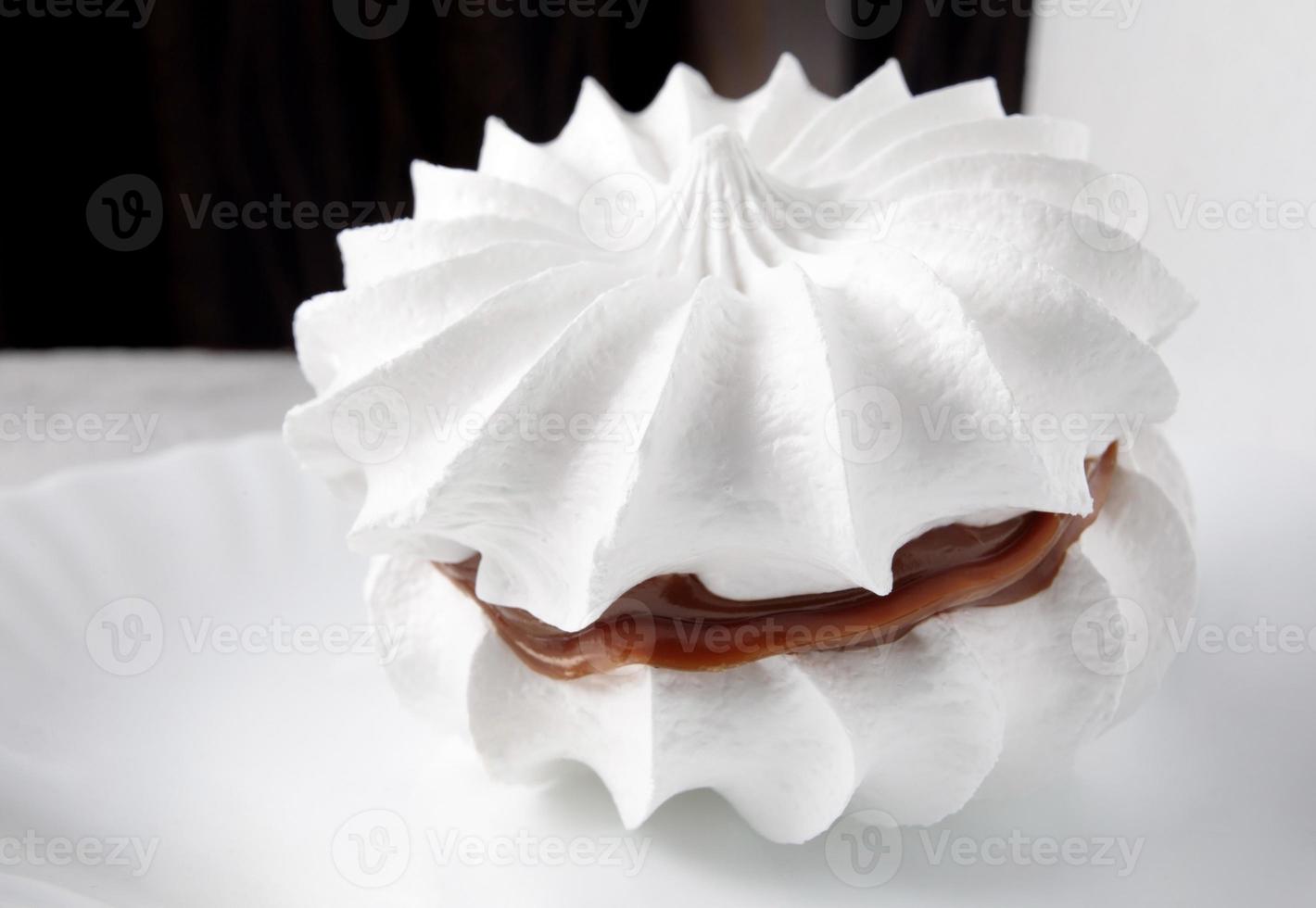 Beautiful white meringues with a silver spoon on a white plate. White cake. photo