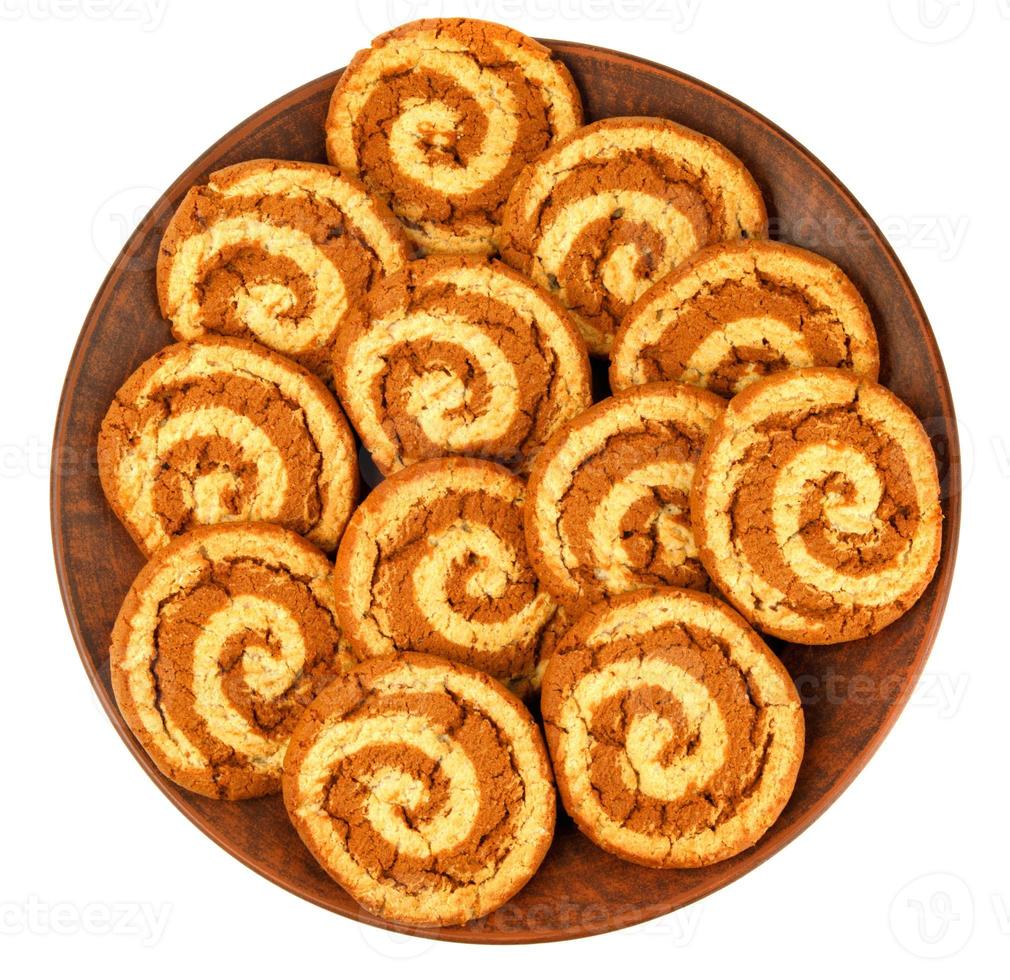 A beautiful cookie with a spiral pattern on a clay plate is isolated on a white background. photo