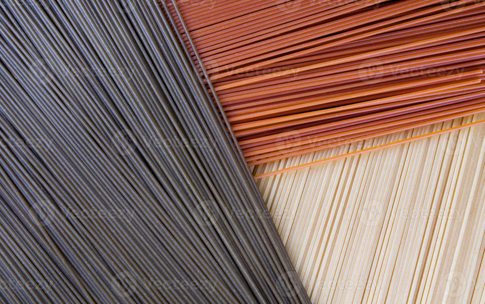 Background from multi-colored pasta. The long pasta in three colors is beautifully laid out. Yellow green and red spaghetti. photo