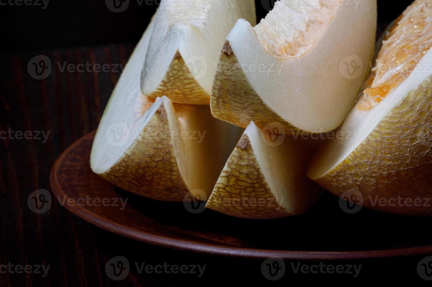 A slices of ripe melon and a half of melon lie on a plate. photo