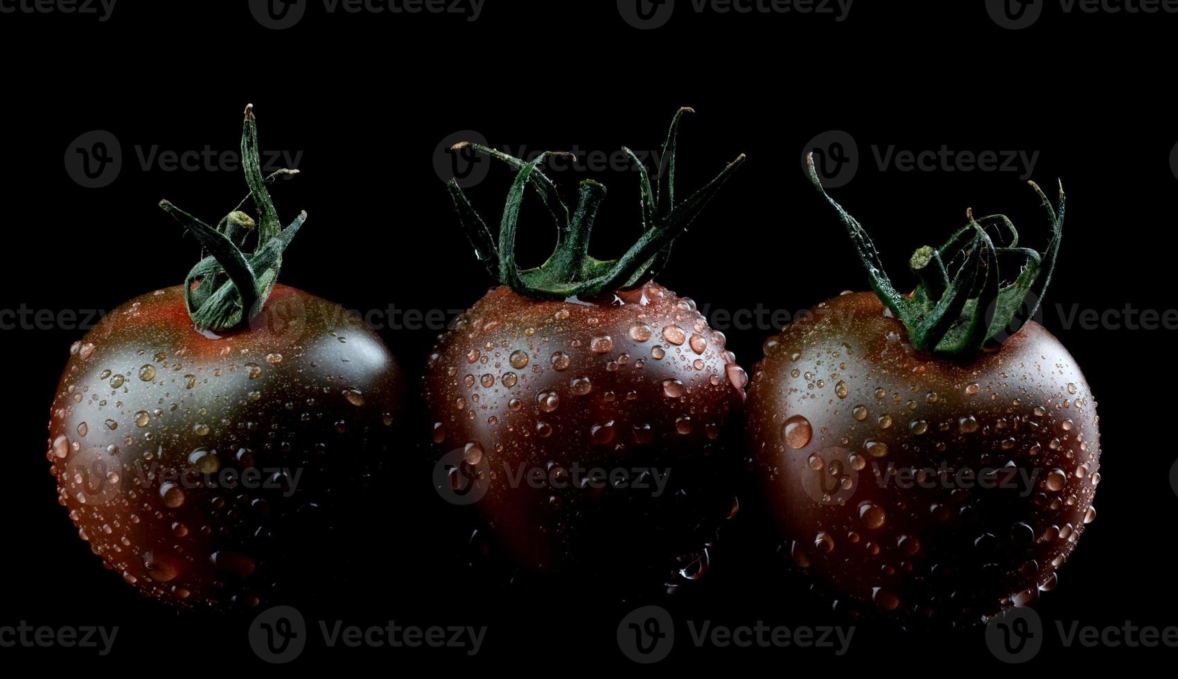 Black tomatoes on a black background. Cherry tomatoes are cumato on a black background. photo