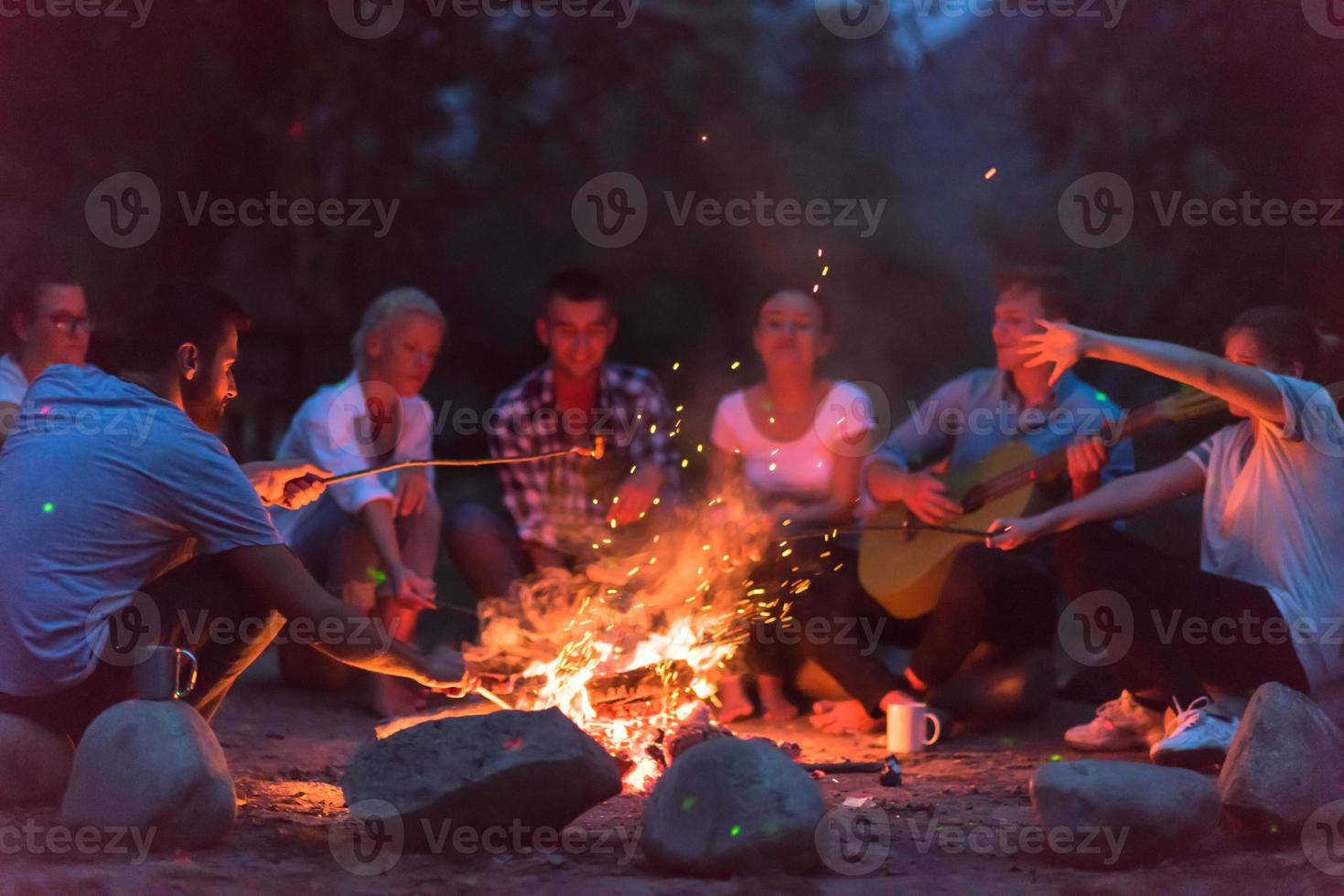 jóvenes amigos relajándose alrededor de una fogata foto