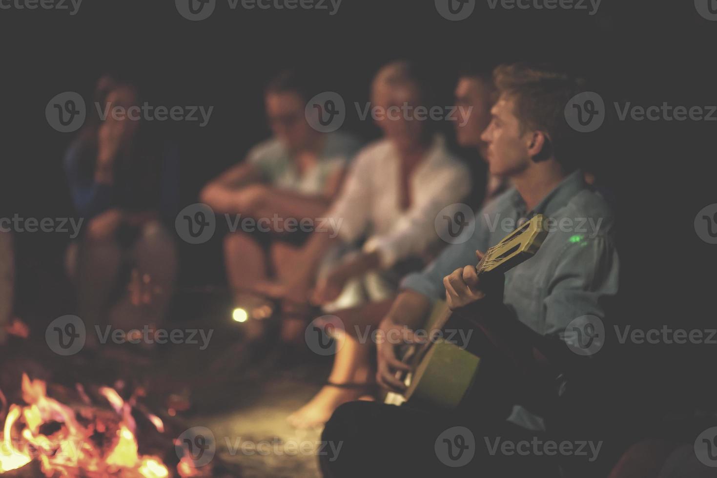 jóvenes amigos relajándose alrededor de una fogata foto