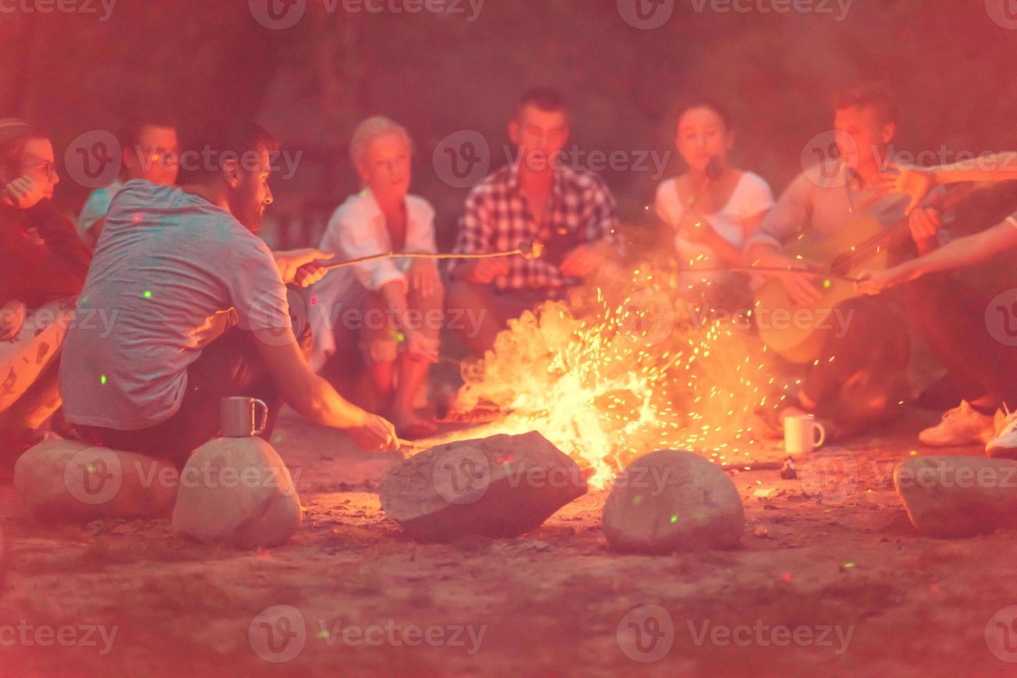young friends relaxing around campfire photo