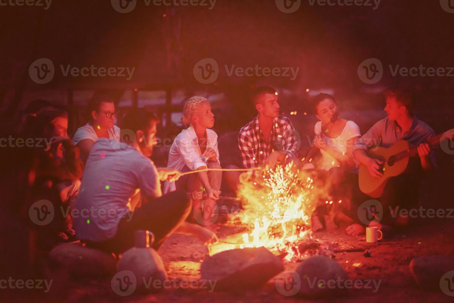 young friends relaxing around campfire photo