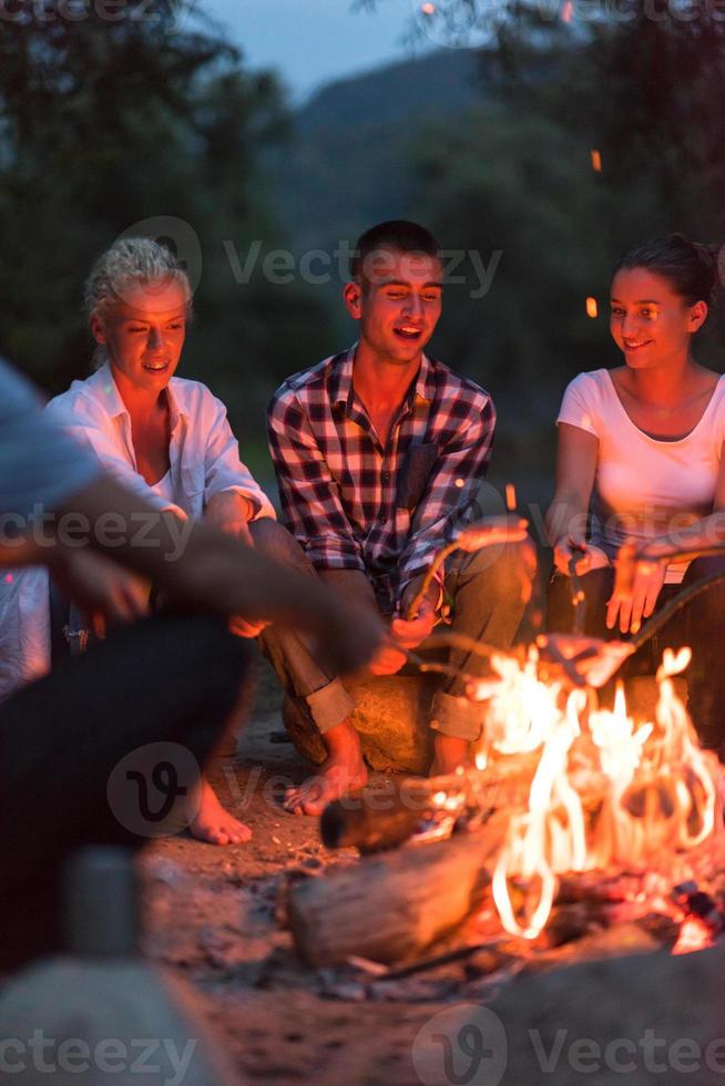 young friends relaxing around campfire photo