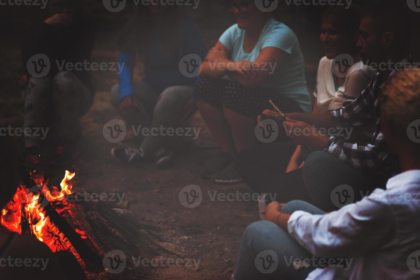 young friends relaxing around campfire photo