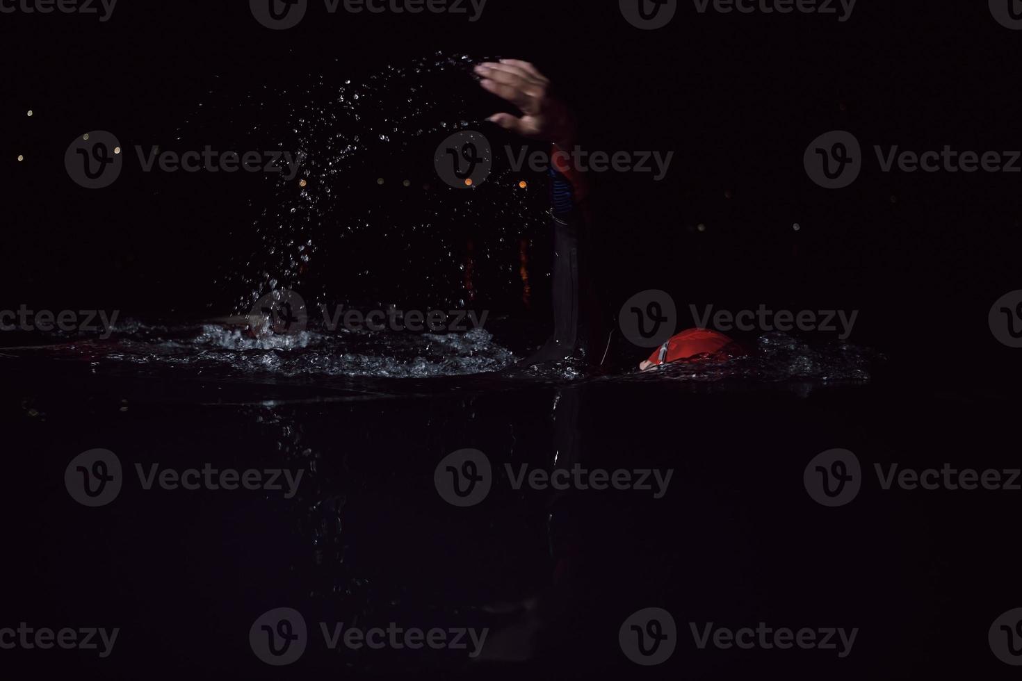 triathlon athlete swimming in dark night  wearing wetsuit photo