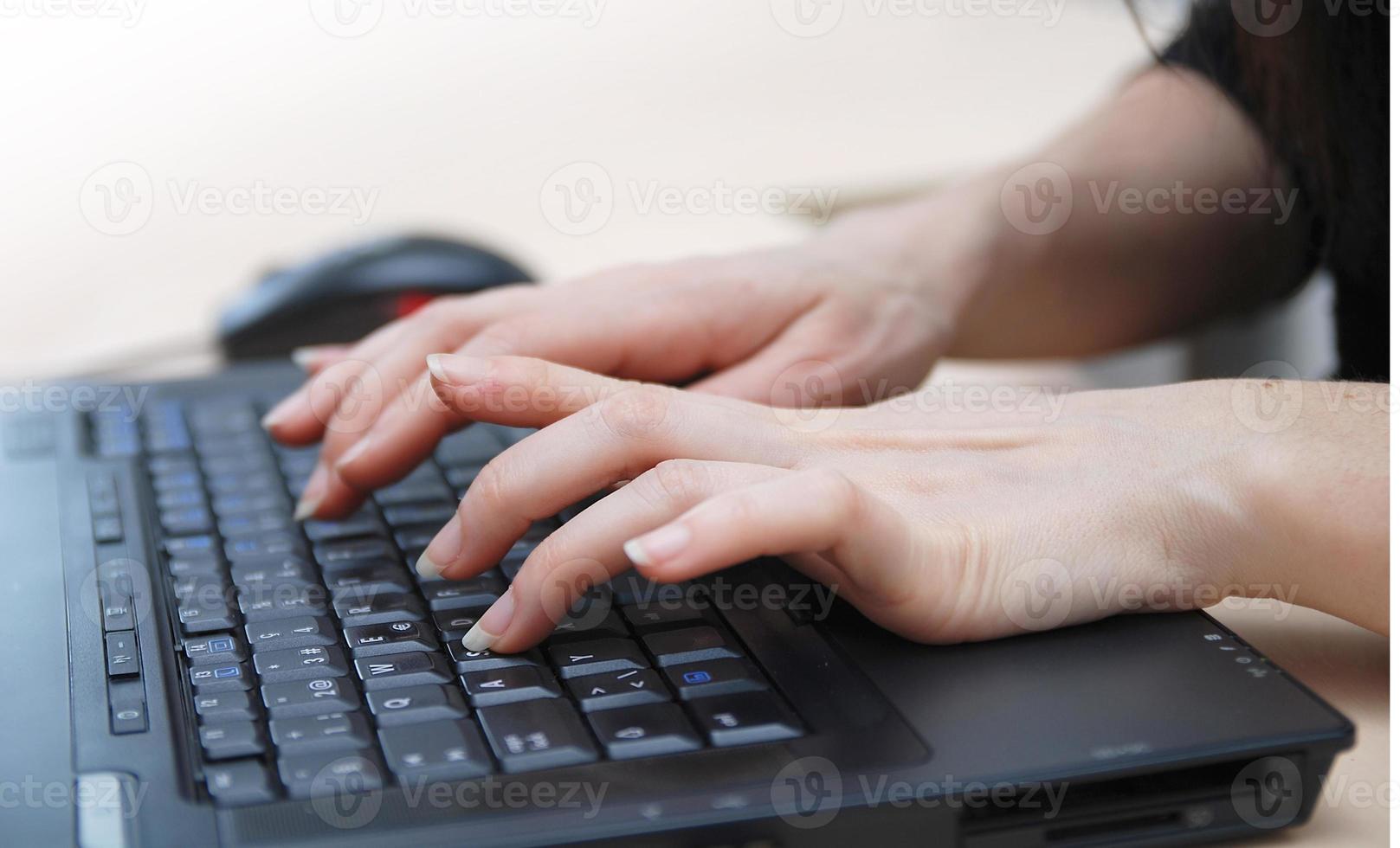 manos de mujer escribiendo en el teclado de la computadora portátil foto