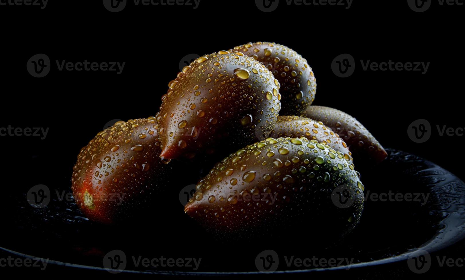 Beautiful ripe cumato tomatoes on a black plate. Cumato tomatoes. photo