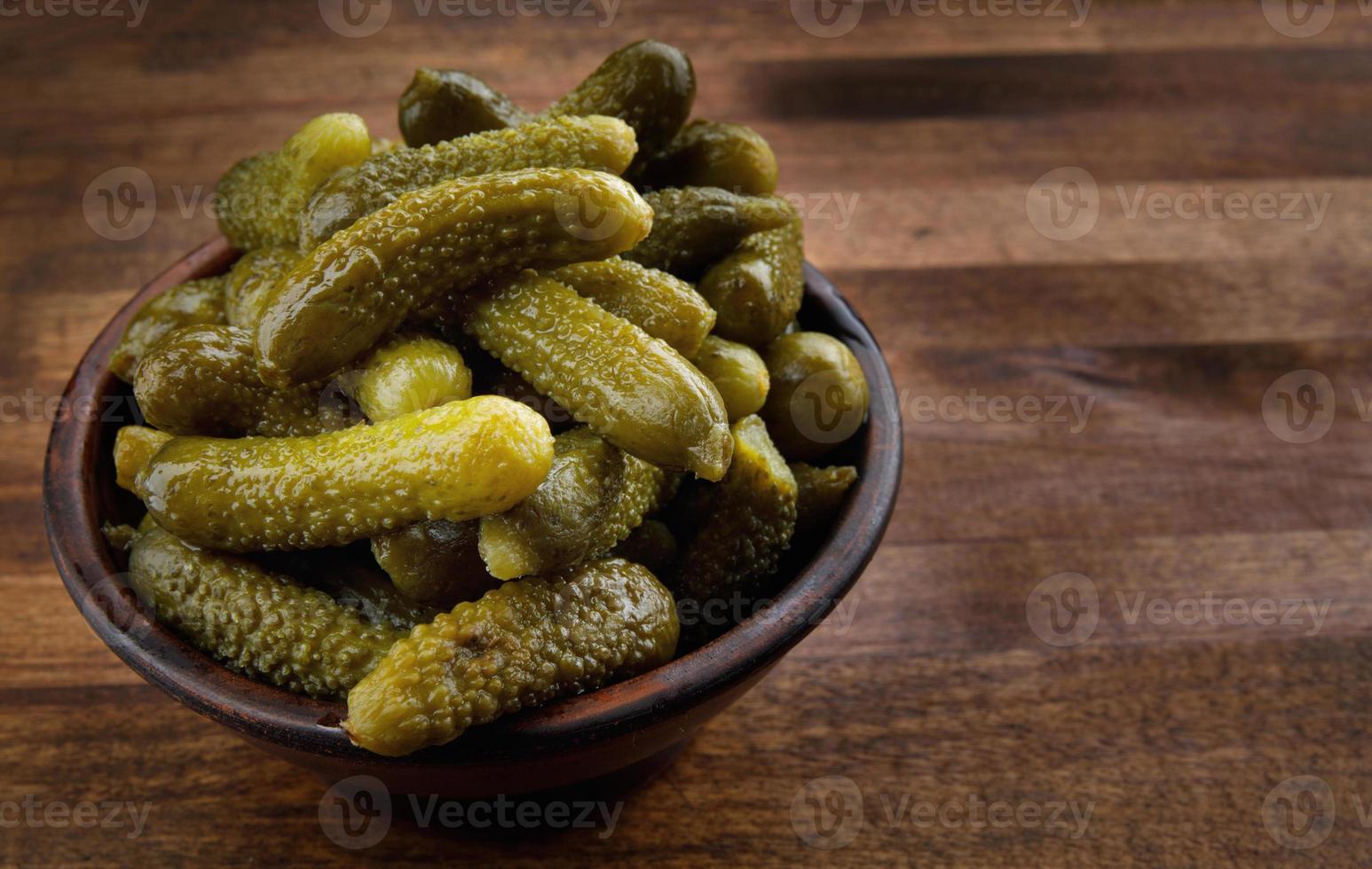A cup of crispy pickled cucumbers stands on a wooden cutting board. Salted cucumbers. photo