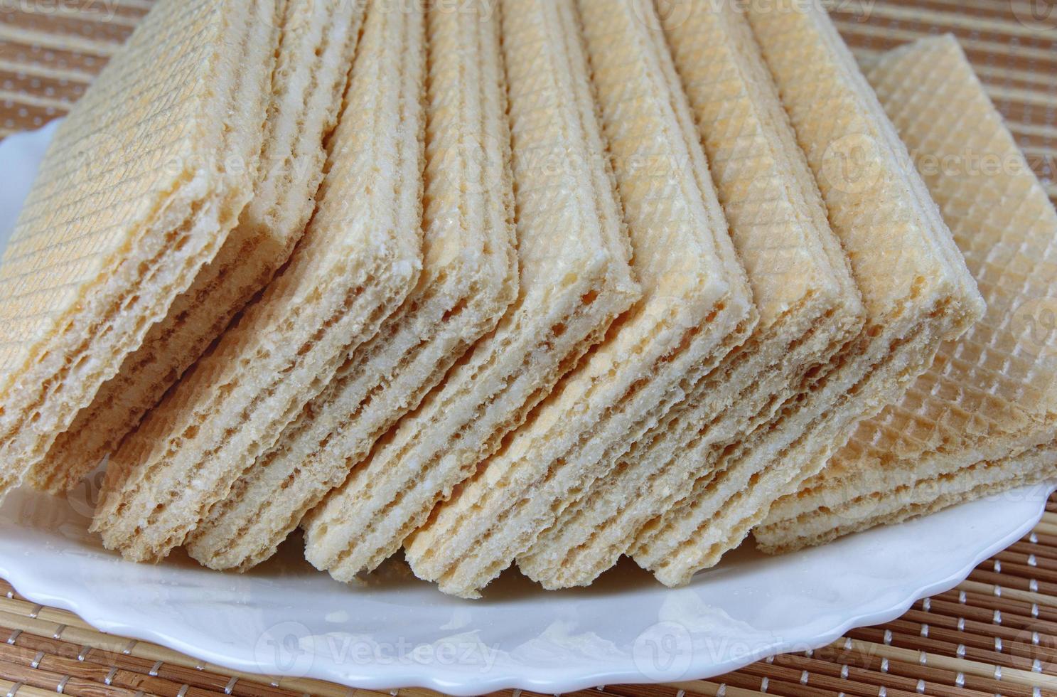 A stack of crisp waffles is on a white plate. photo