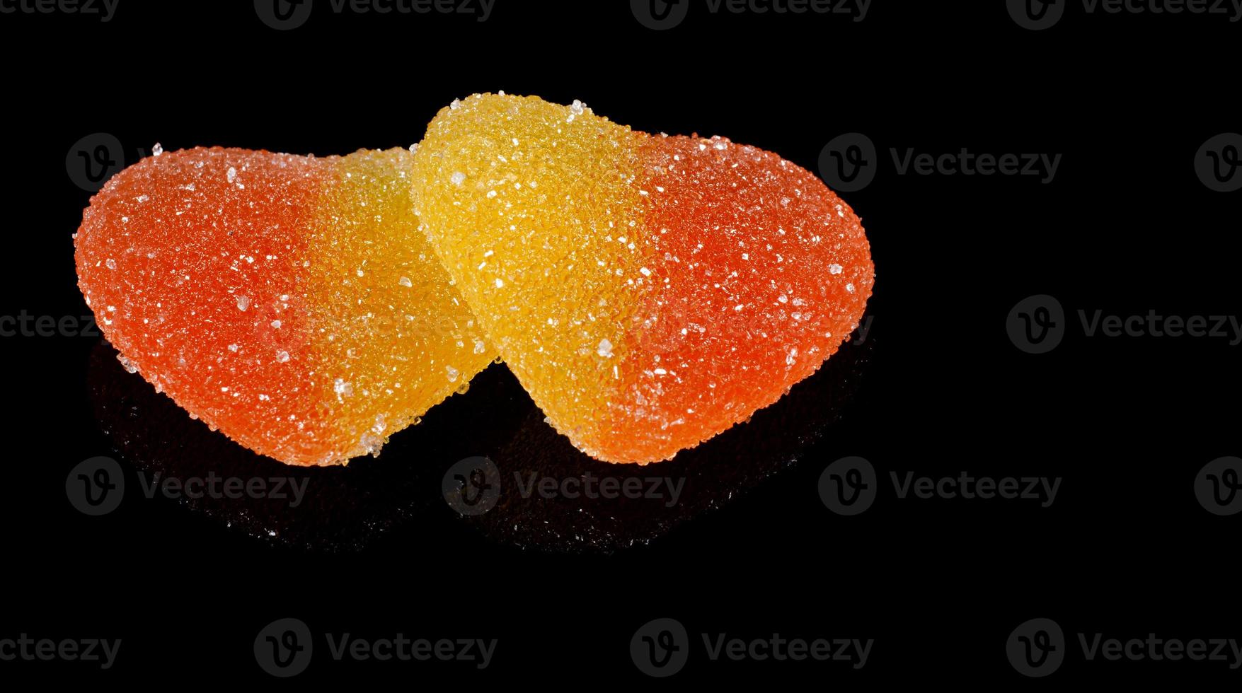 Two marmalade hearts are isolated on a black background. Marmalade candy in the form of a heart. photo