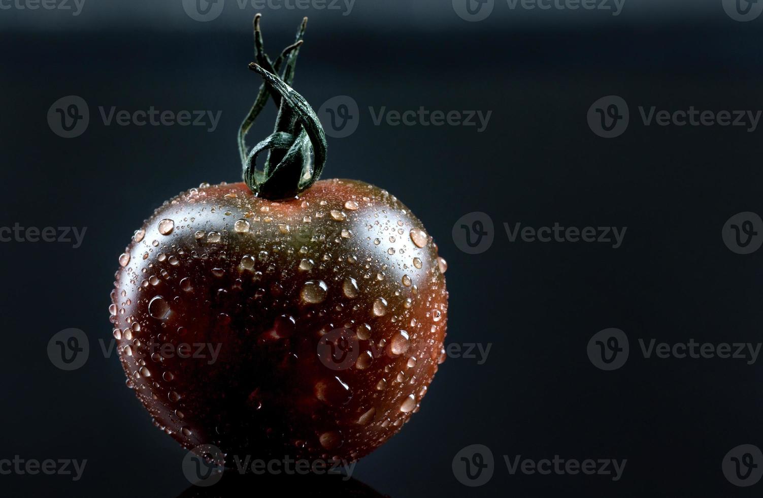 Black tomato on a black background. Cherry tomato is cumato on a black background. photo