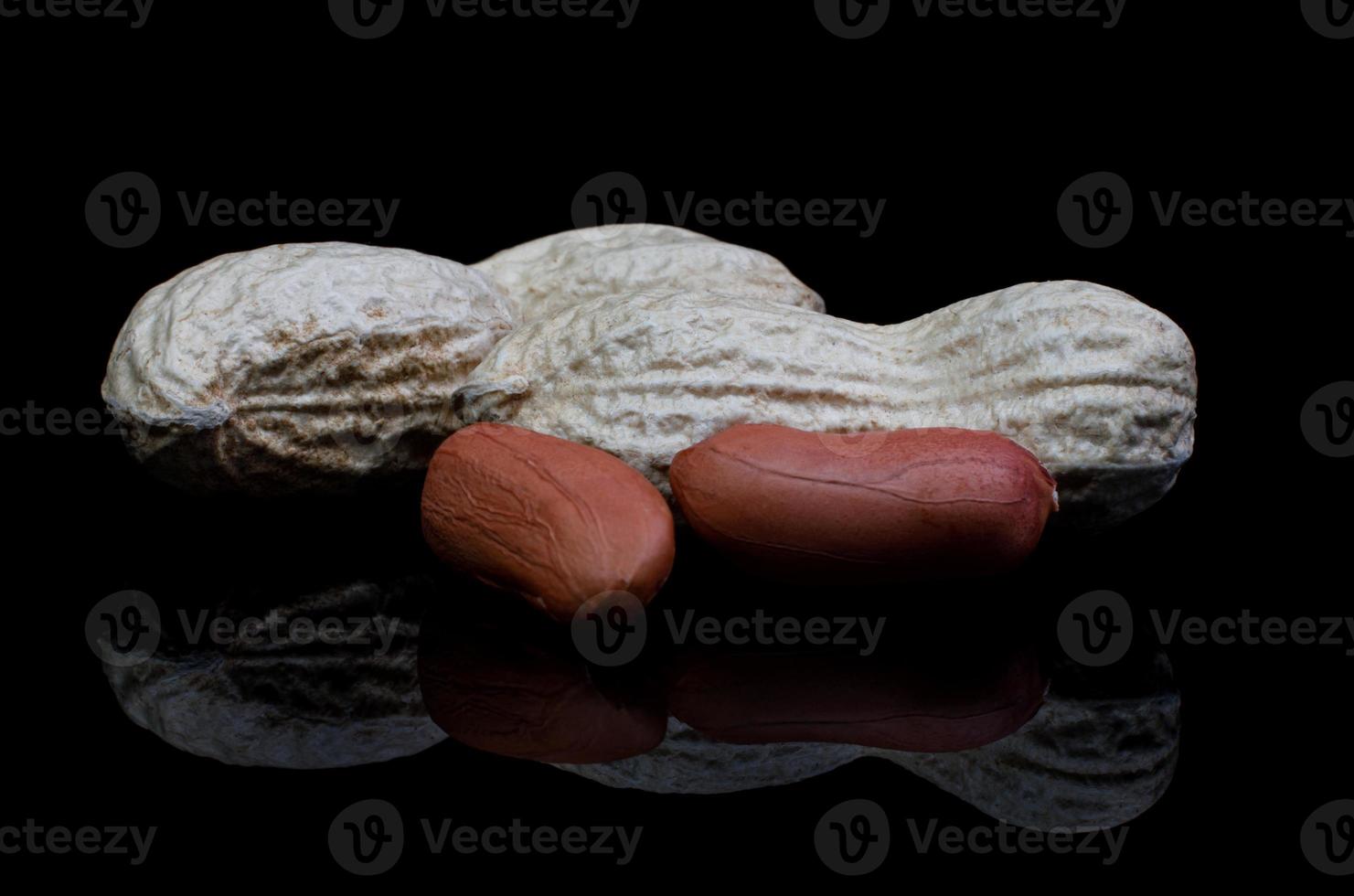 Peanuts in the shell and without it reflect on a black background. photo
