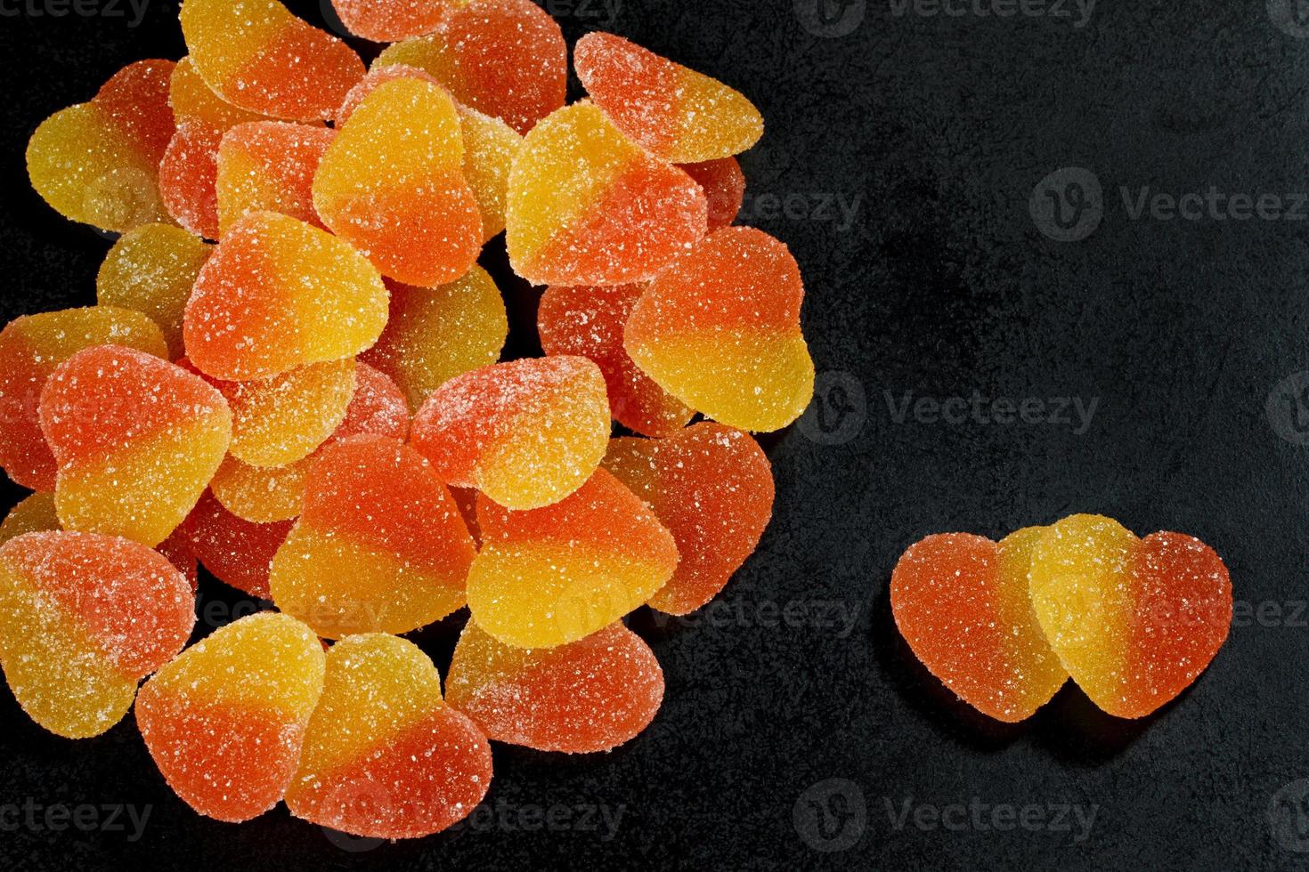 Two heart-shaped sweets next to a lot of sweets. Marmalade candy in the form of a heart. photo