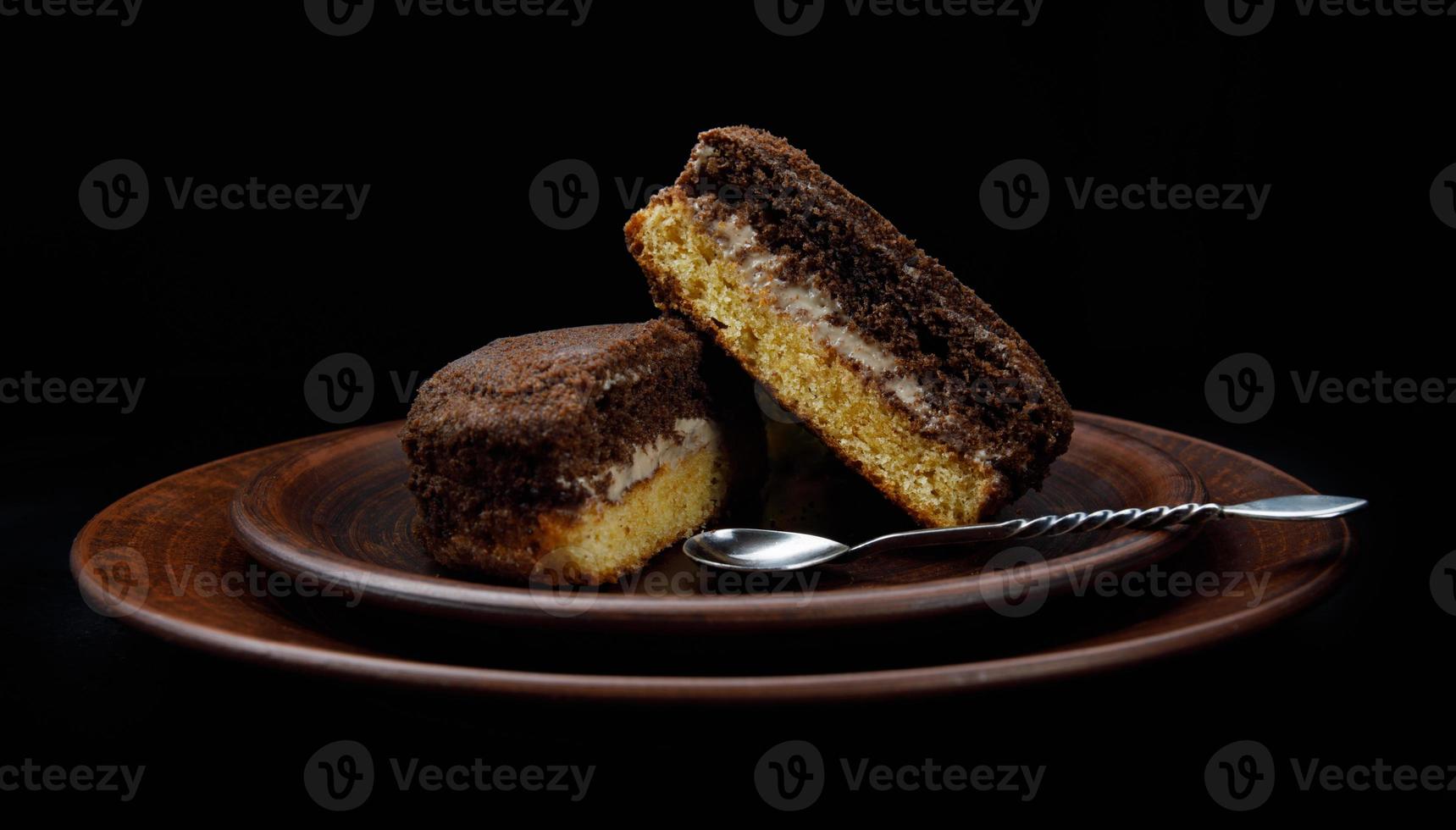 A tiramisu cake with a silver spoon on a clay plate. Side view. photo