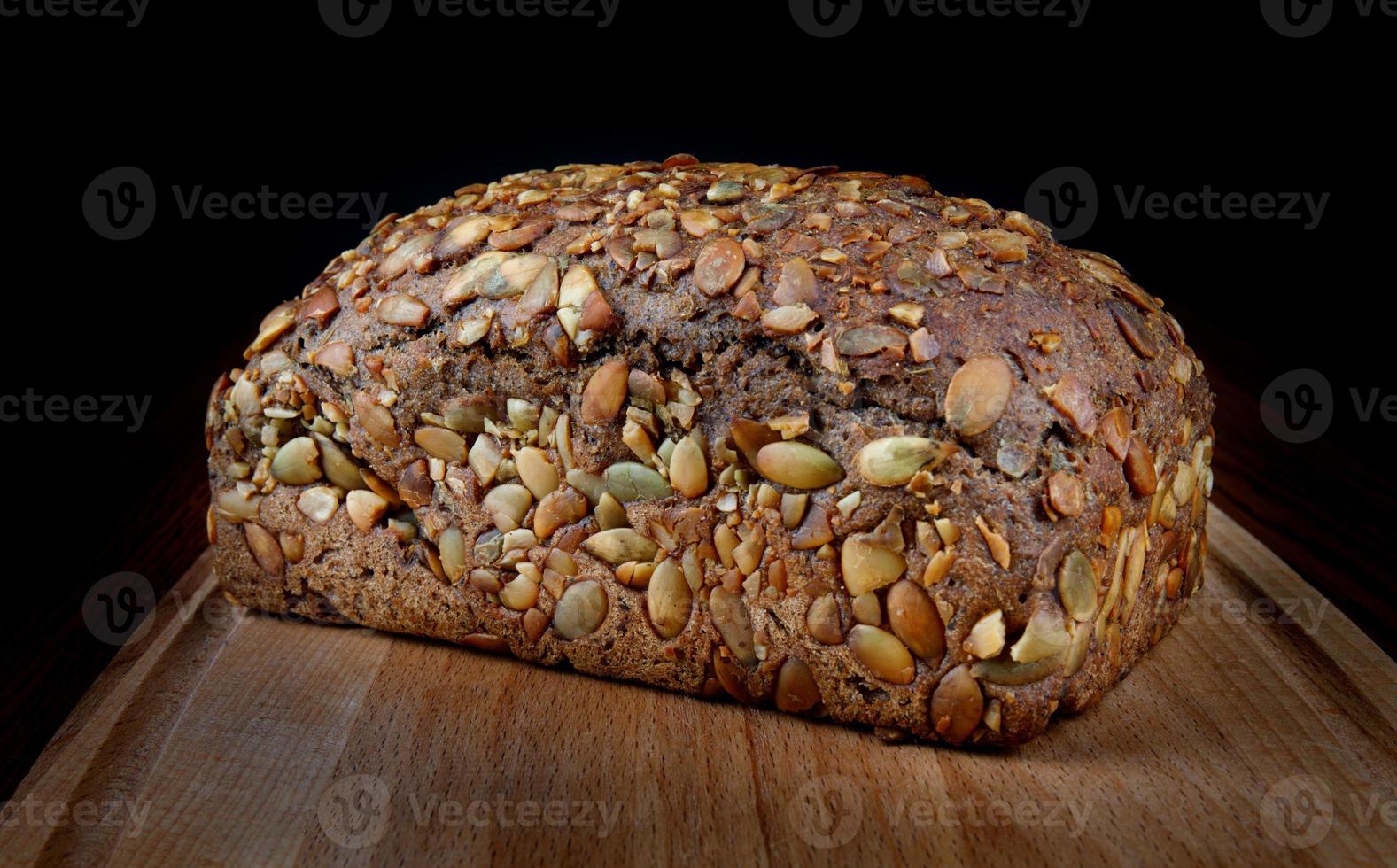 A bread bun with pumpkin seeds on a wooden board. photo