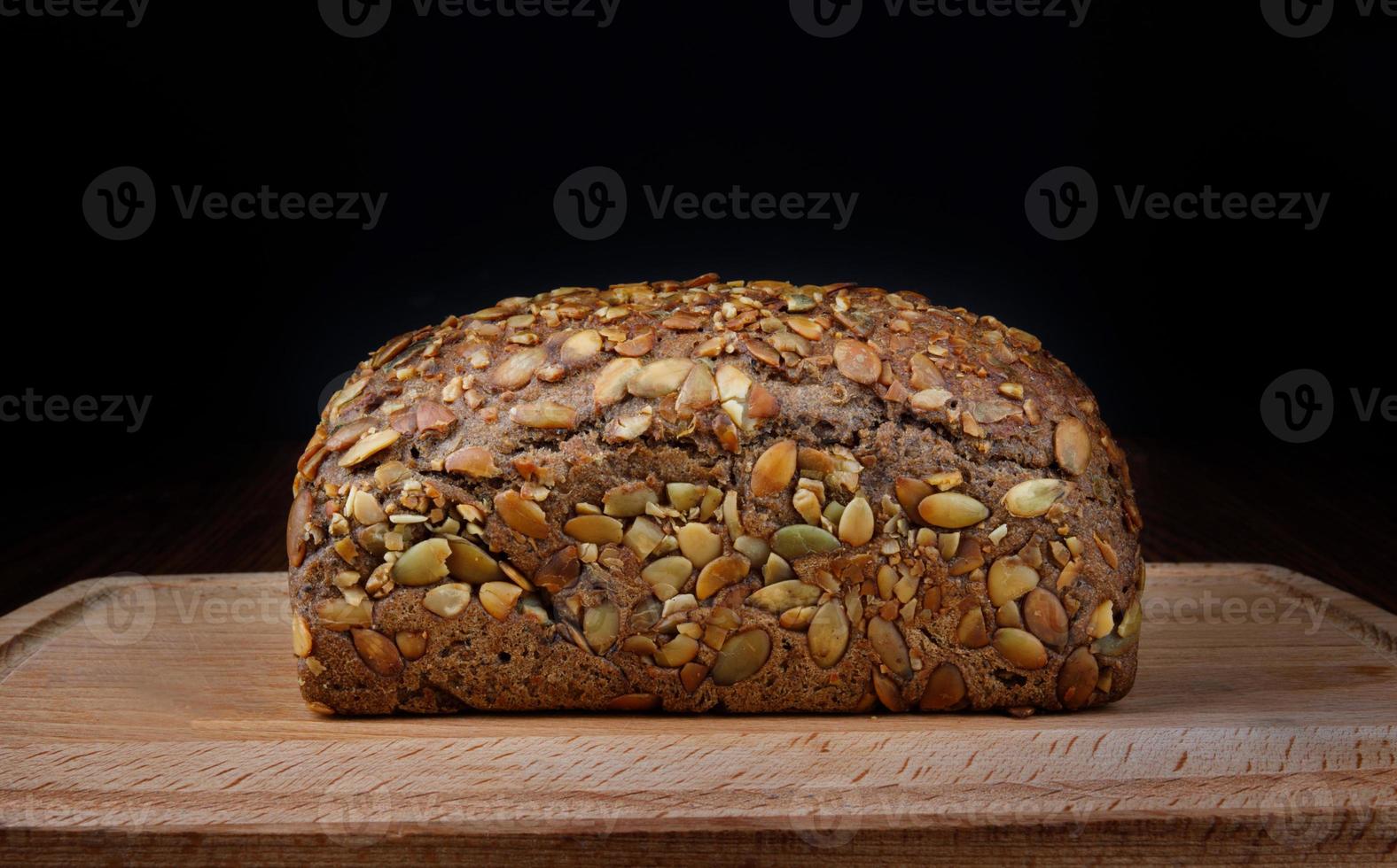 A bread bun with pumpkin seeds on a wooden board. photo